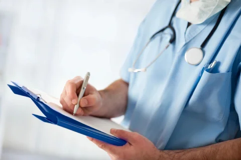 A doctor writing on a pad of paper.